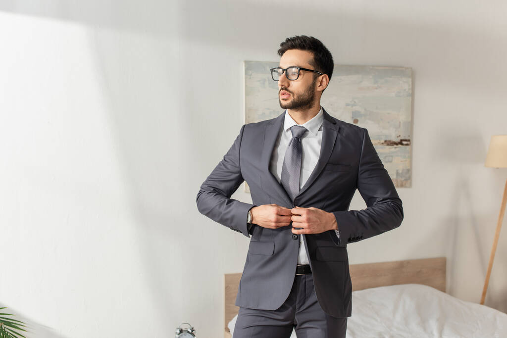 Молодой бизнесмен в очках в пиджаке дома - Фото, изображение