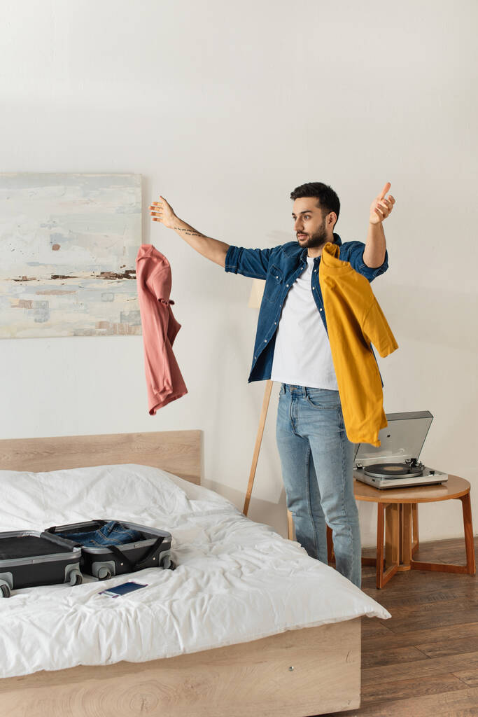 Touristin wirft Kleidung neben Koffer ins Schlafzimmer  - Foto, Bild