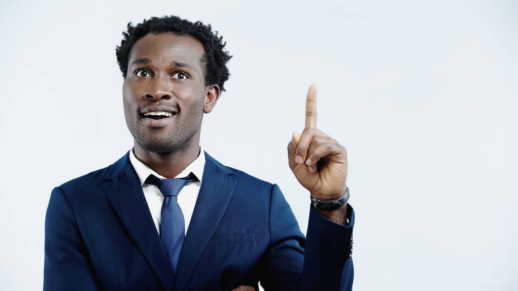 Χαρούμενος Αφροαμερικάνος επιχειρηματίας που δείχνει μια χειρονομία ιδέας απομονωμένη στο μπλε - Φωτογραφία, εικόνα