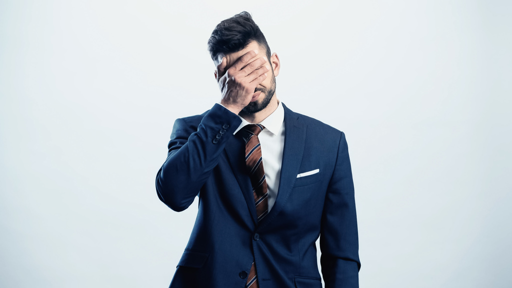καταθλιπτικός επιχειρηματίας που καλύπτει τα μάτια με το χέρι απομονώνονται σε λευκό - Φωτογραφία, εικόνα