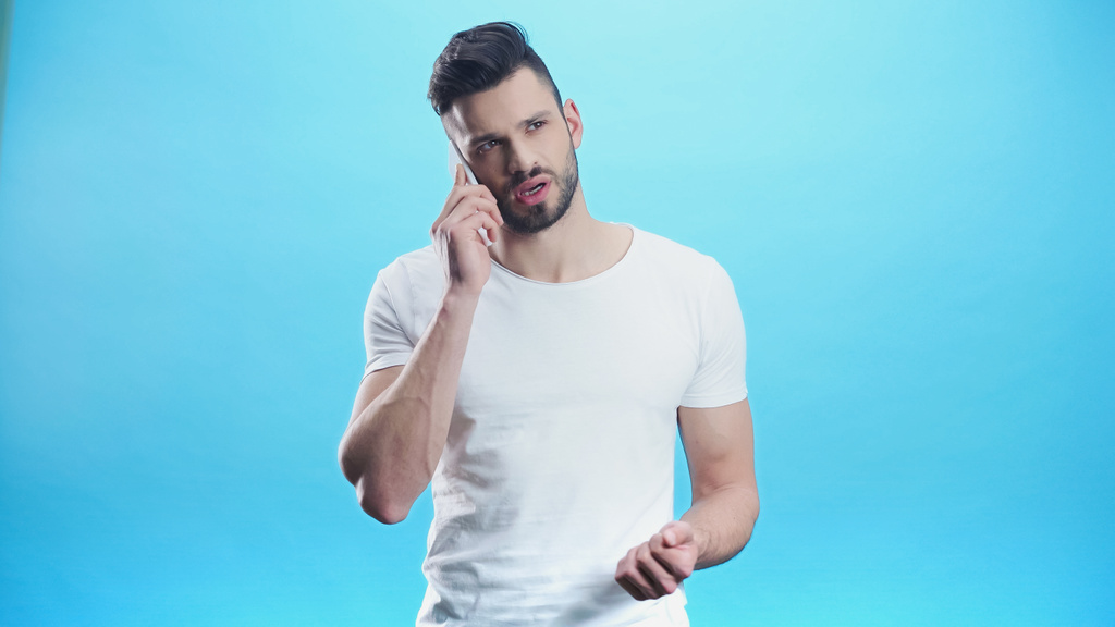 offended man calling on mobile phone isolated on blue - Photo, Image