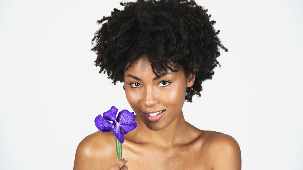 Gri üzerinde mavi orkide tutan güzel Afrikalı Amerikalı kadın.  - Fotoğraf, Görsel