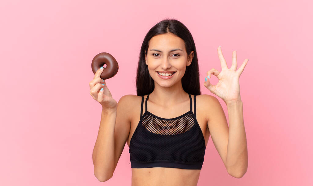 όμορφη γυναίκα γυμναστικής με ένα ντόνατ και ένα μπολ πρωινό - Φωτογραφία, εικόνα