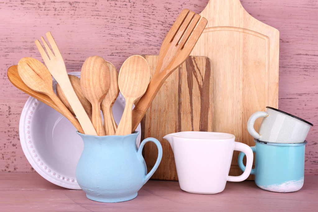 Склад дерев'яних столових приборів, сковороди, чаші та обробної дошки на дерев'яному фоні
 - Фото, зображення