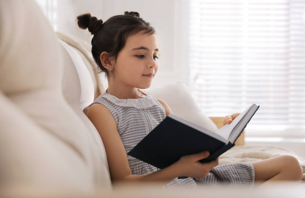Pieni tyttö lukee satua olohuoneessa - Valokuva, kuva