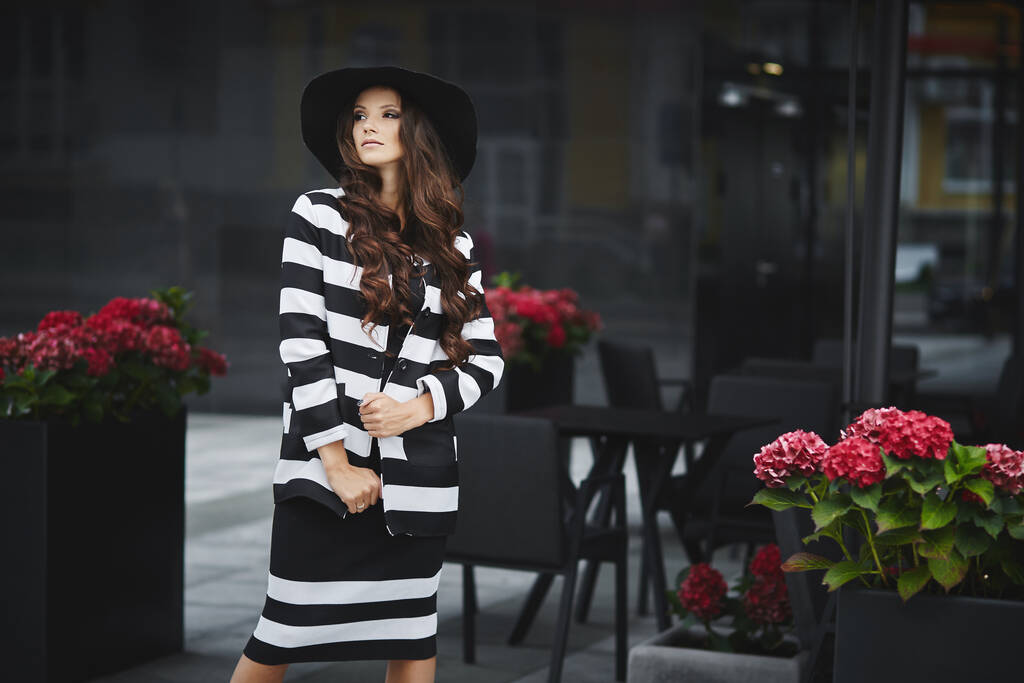 流行のメイクを身に着けている若いモデルの女の子のファッションの肖像ファッションの帽子とドレスは夏の日に屋外でポーズ - 写真・画像