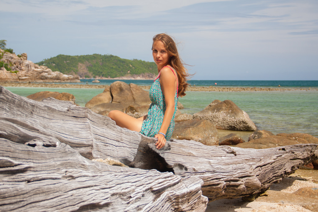 Deniz kenarında bir kayanın üzerine oturmuş elbiseli kız - Fotoğraf, Görsel