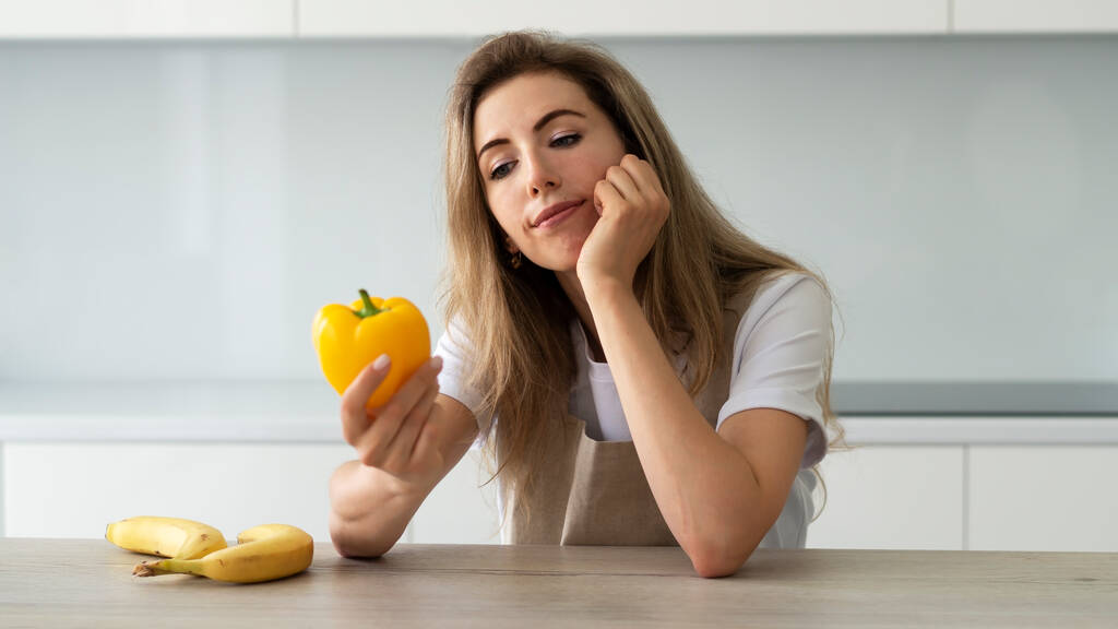 Giovane donna pensierosa pensa ai benefici delle vitamine contenute nelle verdure. Cibo sano e alimentazione sana. - Foto, immagini