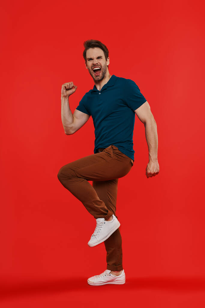 Full length of happy young man in casual wear gesturing against red background - Photo, Image