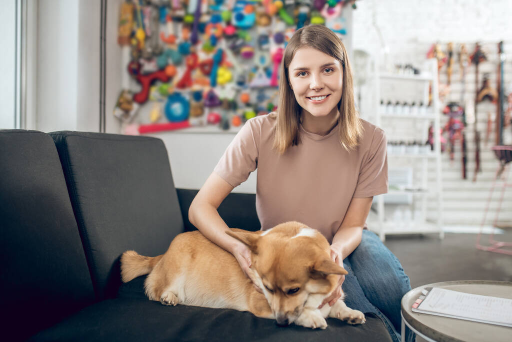 Female pet owner sitting on a sofa with her dog - Photo, Image