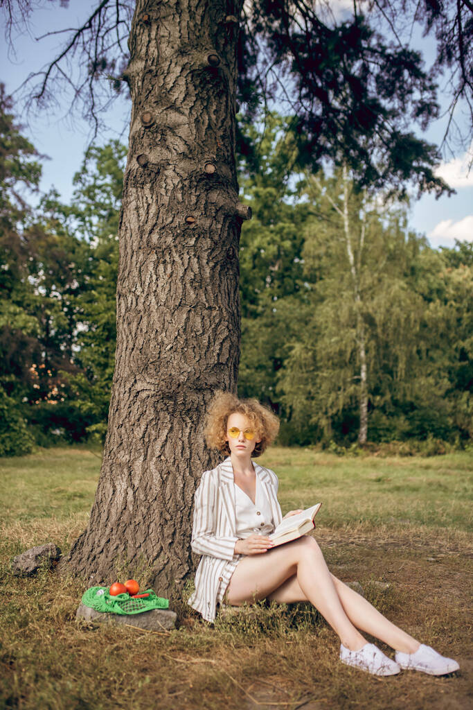 Nuori nainen istuu puun alla puistossa - Valokuva, kuva