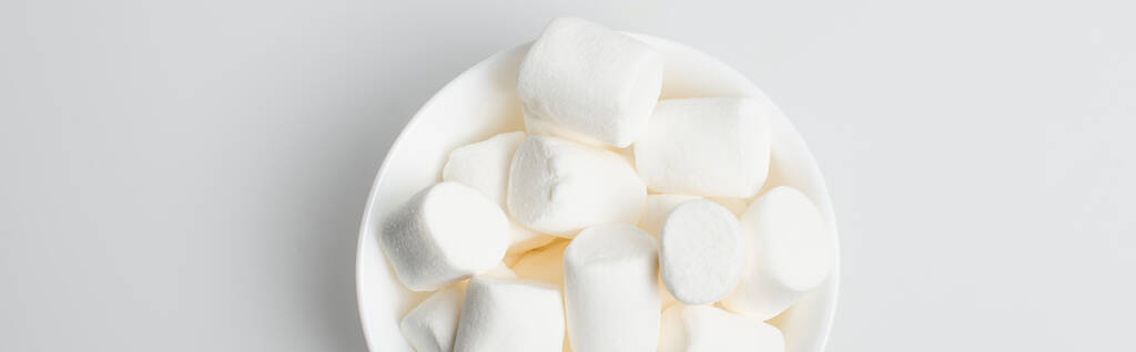 vista dall'alto di marshmallow morbidi e gonfi in ciotola su bianco, banner - Foto, immagini