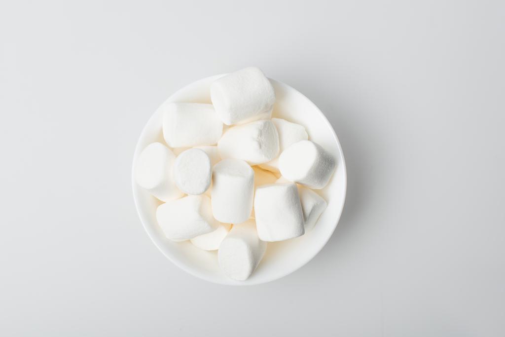 Draufsicht auf weiche und geschwollene Marshmallows in Schale auf Weiß - Foto, Bild
