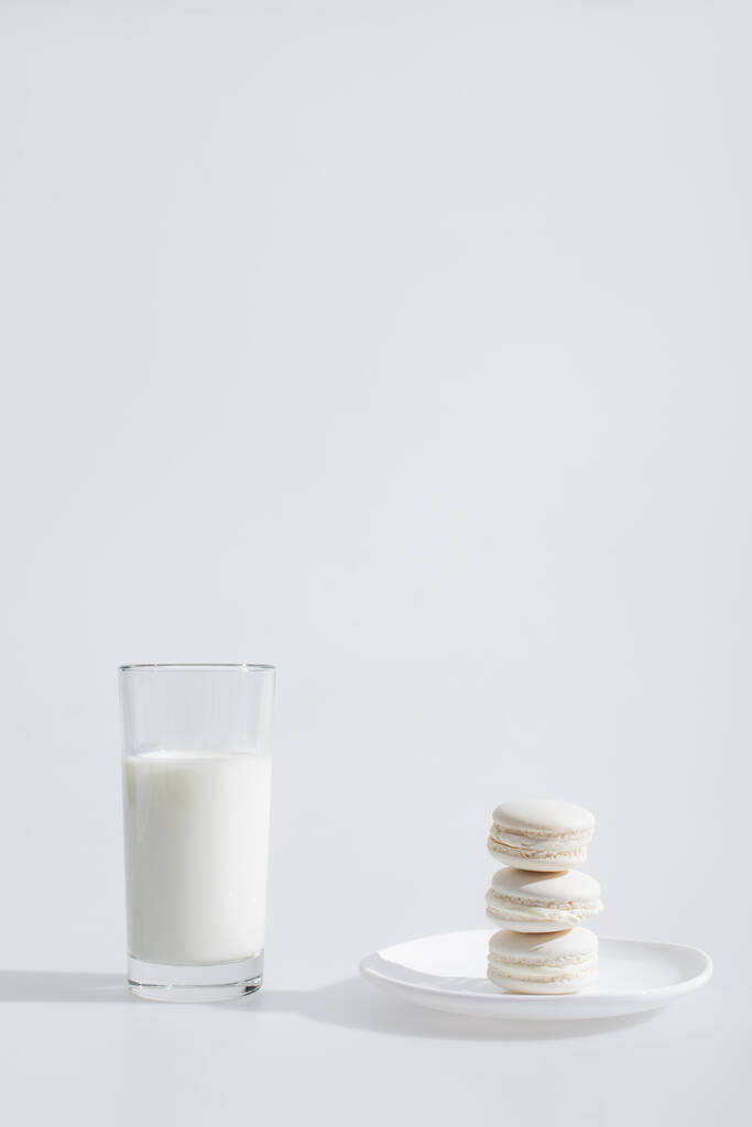 lasillinen maitoa lähellä maukkaita makaroneja lautasella valkoisella - Valokuva, kuva