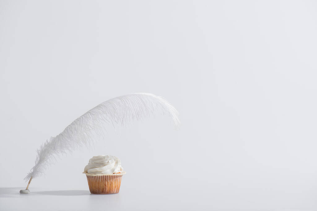 白いカップケーキの近くに無重力羽  - 写真・画像