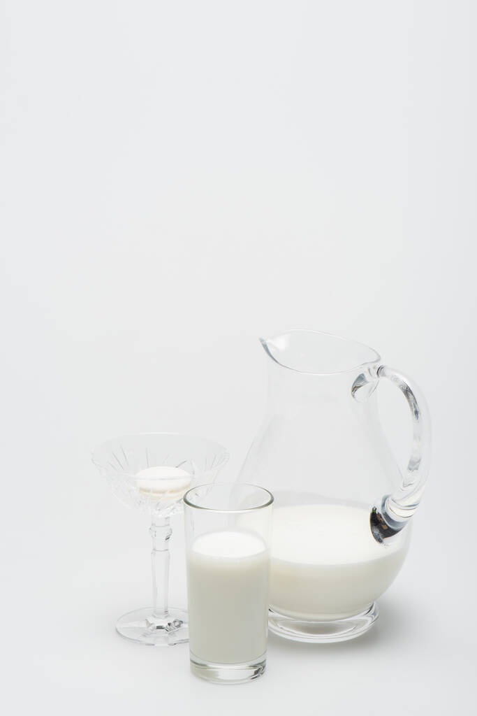 macaron in dessertgerecht bij glas melk en kruik op wit - Foto, afbeelding