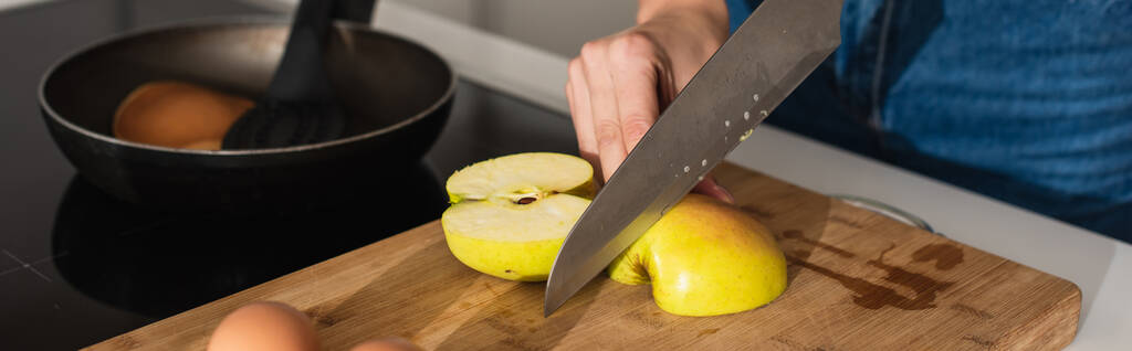 Vista recortada de la mujer cortando manzana cerca de huevos y sartén, pancarta  - Foto, imagen