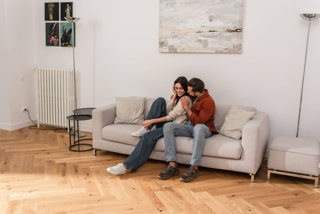 Man embracing smiling girlfriend on couch  - Photo, Image