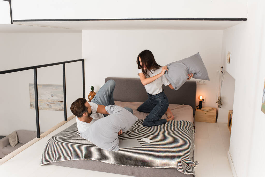 Iloinen nainen tyyny taistelevat poikaystävä sängyssä  - Valokuva, kuva