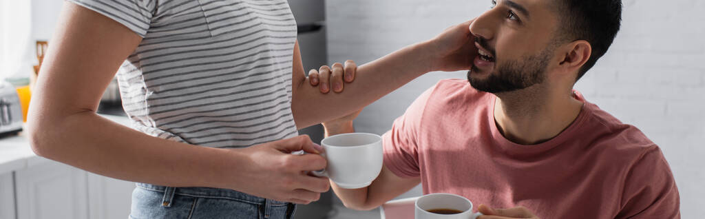 vista recortada de la mujer joven tocando novio y sosteniendo taza con café, pancarta - Foto, Imagen