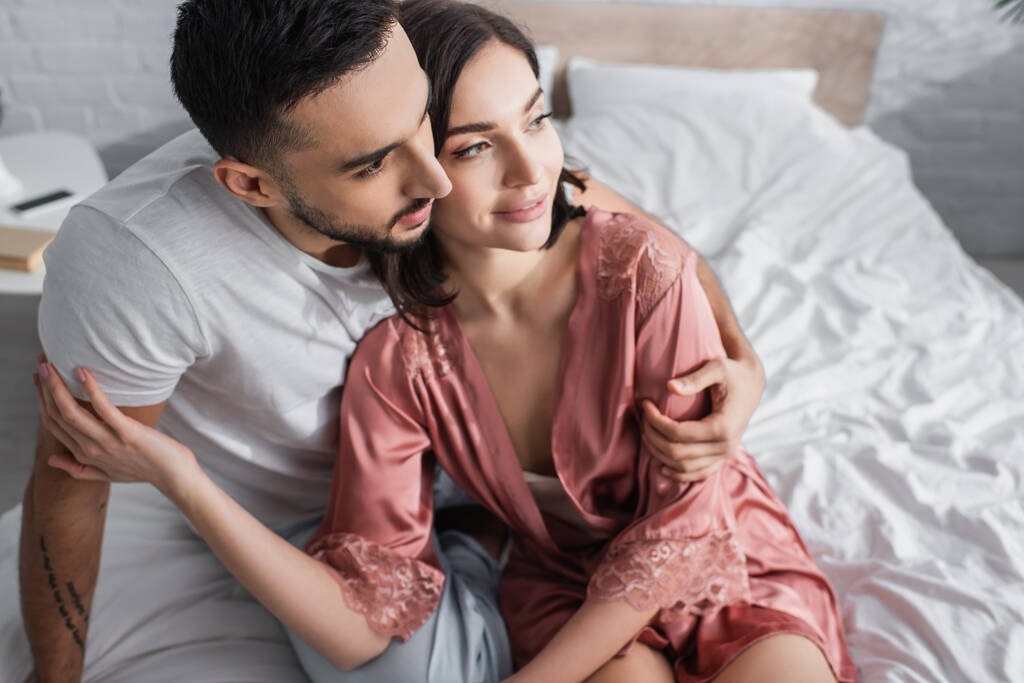 high angle view of smiling young couple gently hugging in bedroom - Photo, Image