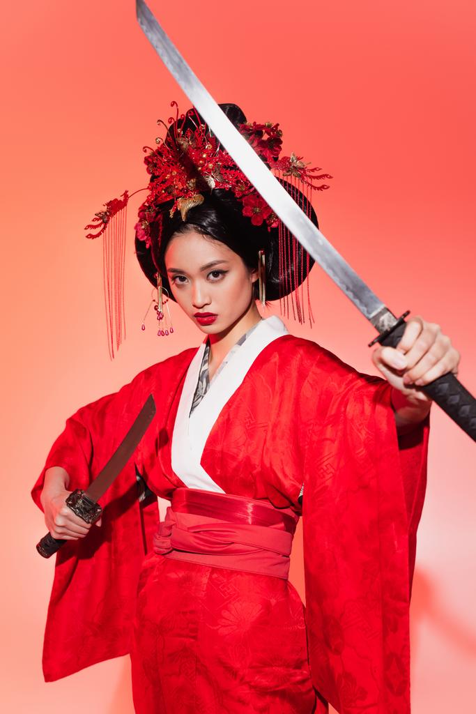 Японка тримає мечі на червоному фоні.  - Фото, зображення