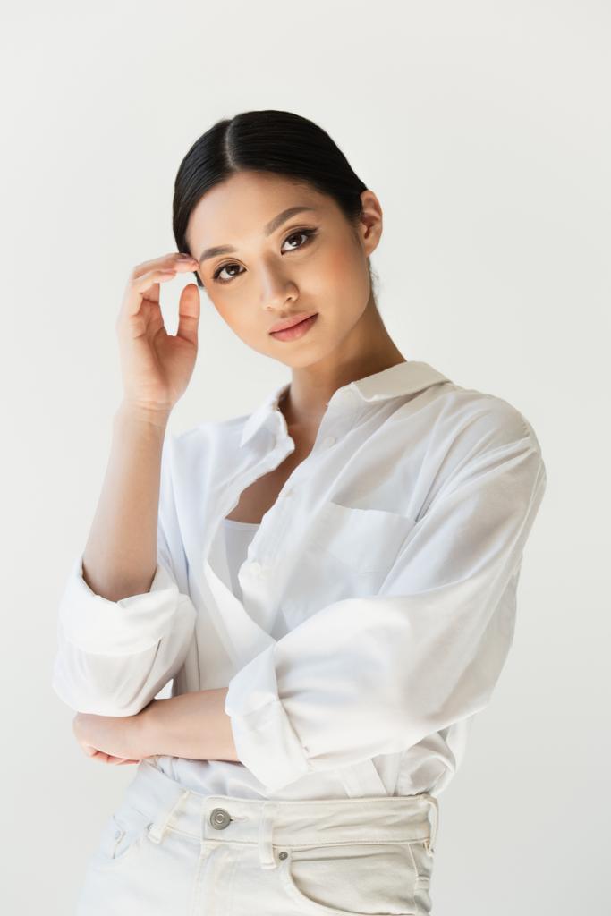 Asiatische Frau in weißen Kleidern blickt auf Kamera isoliert auf grau - Foto, Bild