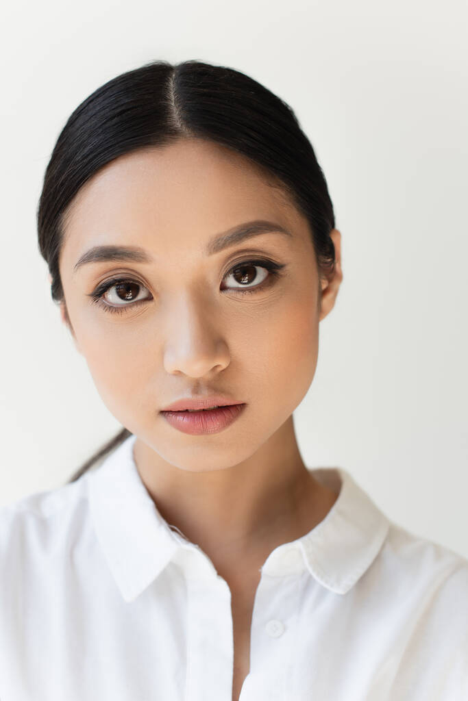 Porträt einer asiatischen Frau, die die Kamera isoliert auf grau betrachtet - Foto, Bild