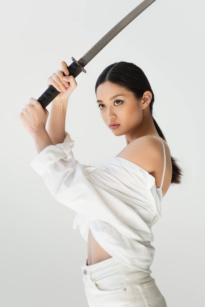 Aasialainen nainen paita tilalla miekka ja etsivät pois eristetty harmaa - Valokuva, kuva