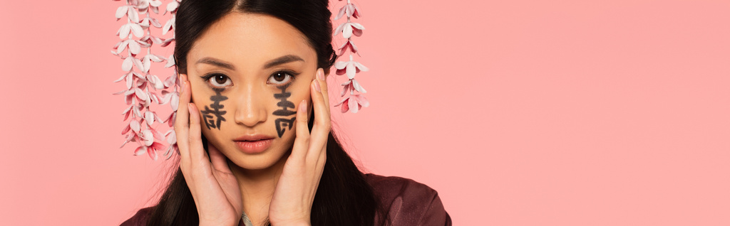 Portrait of asian woman with hieroglyphs of face isolated on pink, banner  - Photo, Image