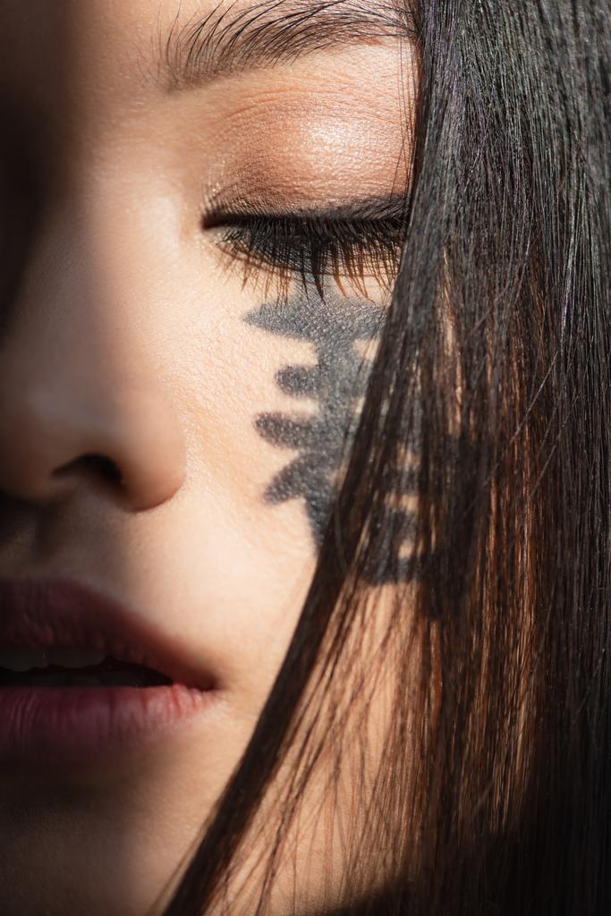 Close up view of japanese woman with hieroglyphs and closed eye - Photo, Image