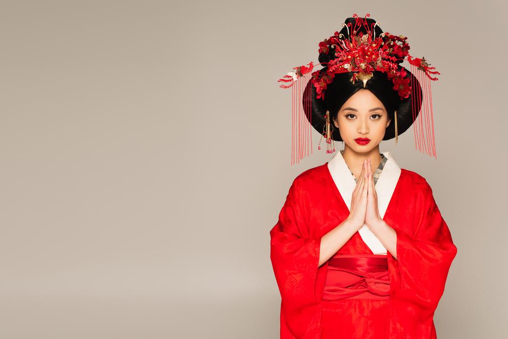 asiatico donna con rosso labbra mostrando pregando mani isolato su grigio  - Foto, immagini