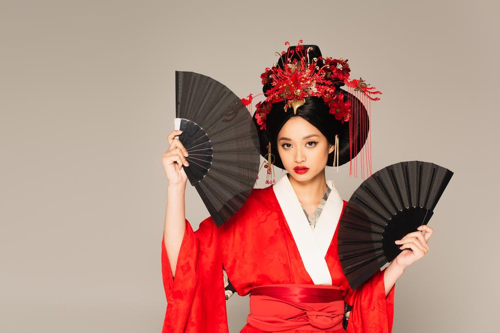 Asiatin im Kimono hält schwarze Fans isoliert auf grau  - Foto, Bild