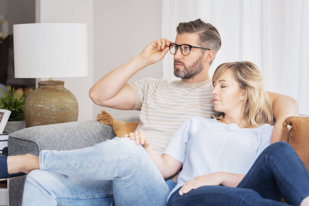 Foto de una pareja afectuosa relajándose juntos en su sala de estar en casa. Hombre guapo viendo la televisión mientras su hermosa esposa dormía a su lado.  - Foto, imagen