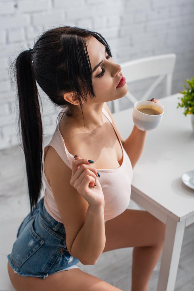 visão de alto ângulo da jovem morena segurando xícara de café - Foto, Imagem