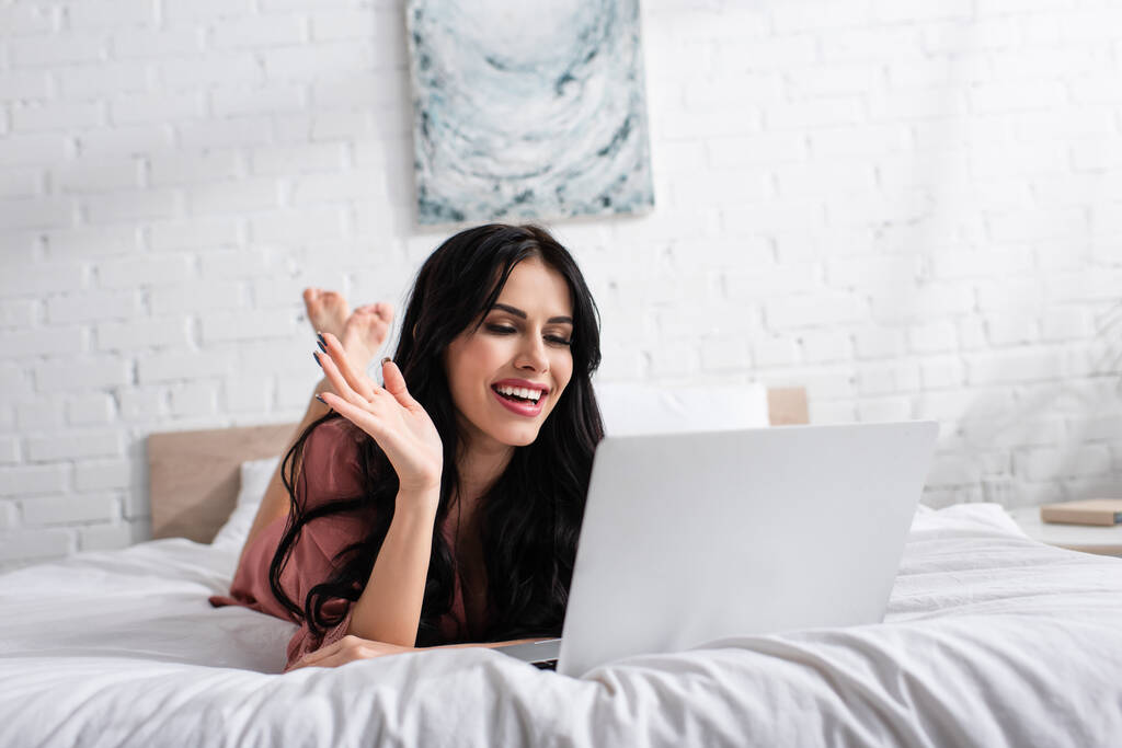 cheerful young woman waving hand during video call on laptop  - Photo, Image
