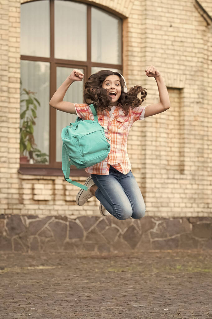 Fröhlicher, energiegeladener Kindersprung mit Schultüte in lässiger Manier auf dem Schulhof, Ferien - Foto, Bild