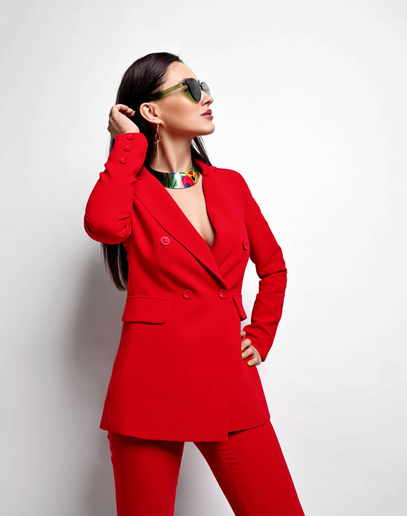 Porträt einer jungen arroganten brünetten Geschäftsfrau in roter offizieller Strumpfhose und Sonnenbrille, die zur Seite schaut - Foto, Bild