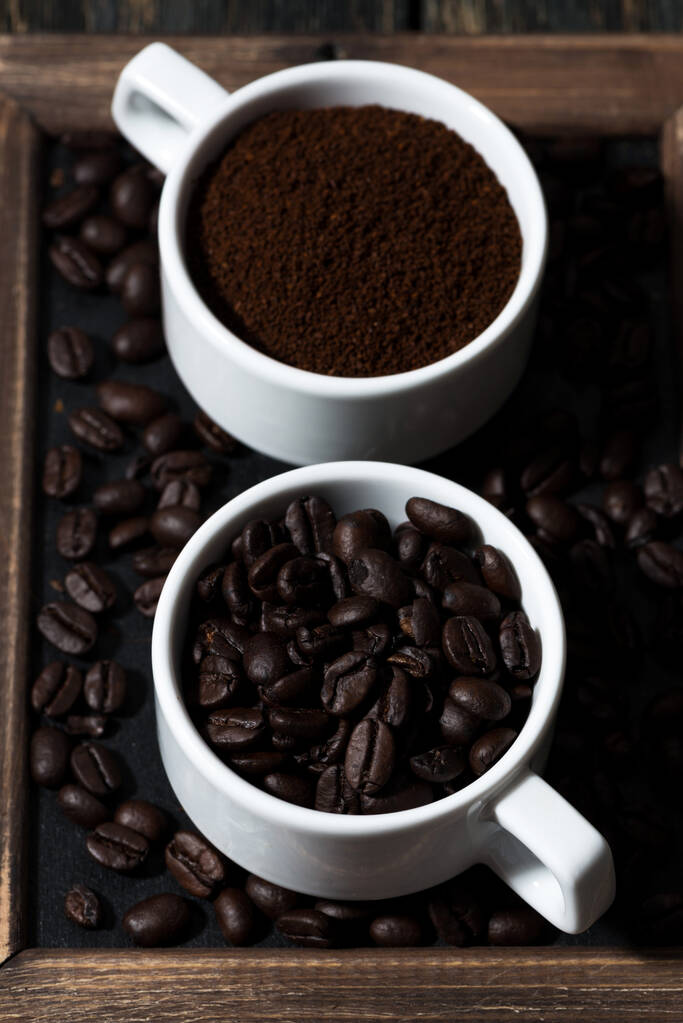 gemahlener Kaffee und Kaffeebohnen in Tassen, vertikal, Nahaufnahme - Foto, Bild