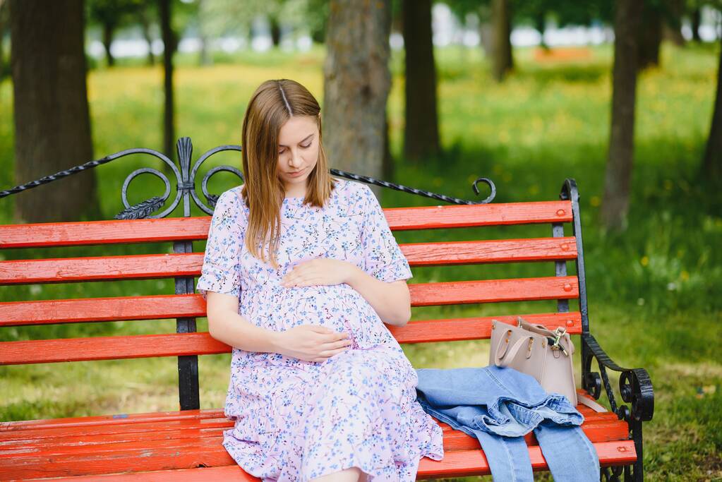 Όμορφη έγκυος γυναίκα χαλαρώνοντας στο πάρκο - Φωτογραφία, εικόνα