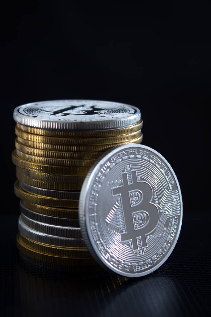 Jeden srebrny bitcoin i stos bitcoinów na ciemnym tle - Zdjęcie, obraz