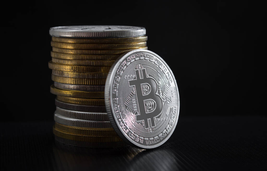 Un bitcoin de plata y una pila de bitcoins sobre fondo negro - Foto, Imagen