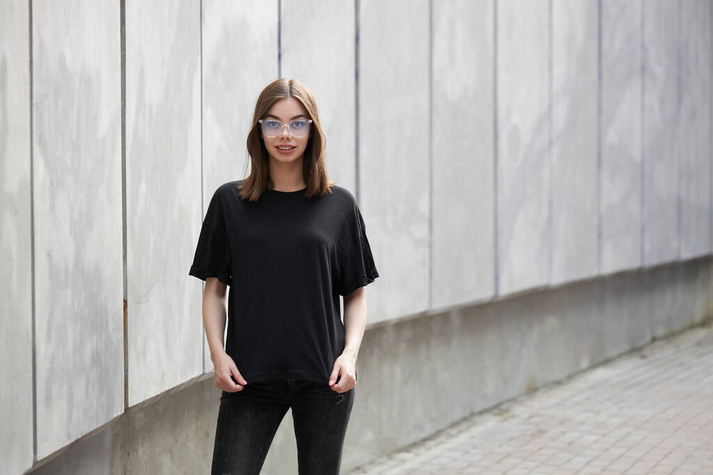 Nő vagy lány visel fekete üres pamut póló helyet a logó, gúnyolódni, vagy design alkalmi városi stílusban - Fotó, kép