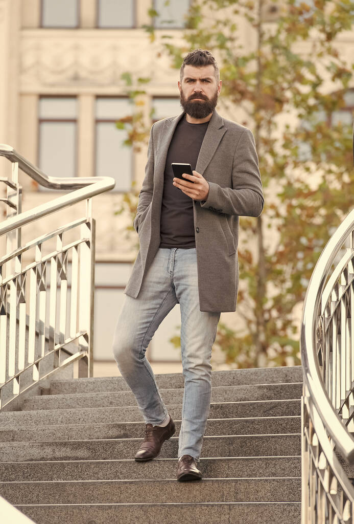 Ocupado hipster en estilo casual de negocios bajar escaleras sosteniendo el teléfono móvil urbano al aire libre, hombre - Foto, Imagen