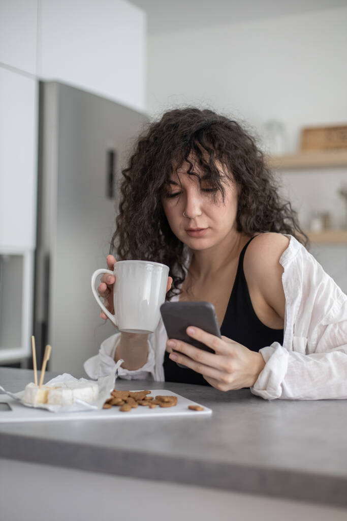 Молодий домашній жіночий набір смс-повідомлень спілкуються соціальними мережами на білій скандинавській кухні
 - Фото, зображення