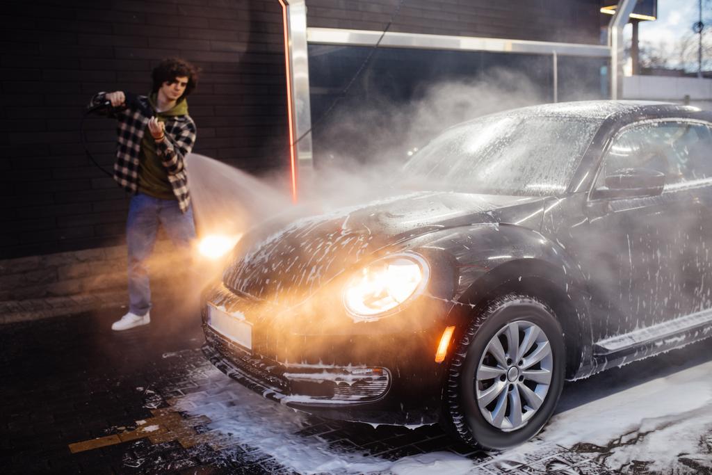 Αυτοκίνητο σε αφρό κοντά θολή οδηγού με πλυντήριο πίεσης σε εξωτερικούς χώρους  - Φωτογραφία, εικόνα