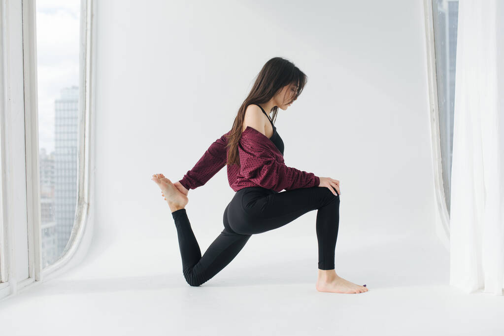 Seitenansicht einer armenischen Frau, die zu Hause Yoga in Bogenpose praktiziert - Foto, Bild