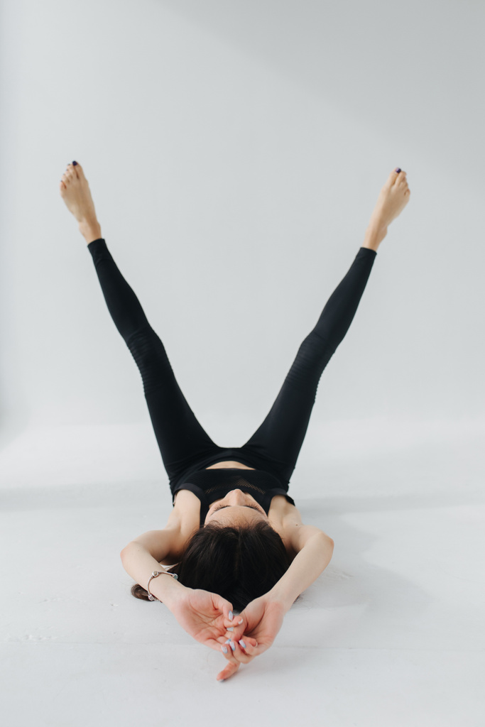 barefoot armenian woman in black leggings practicing yoga in rejuvenation pose on white - Photo, Image