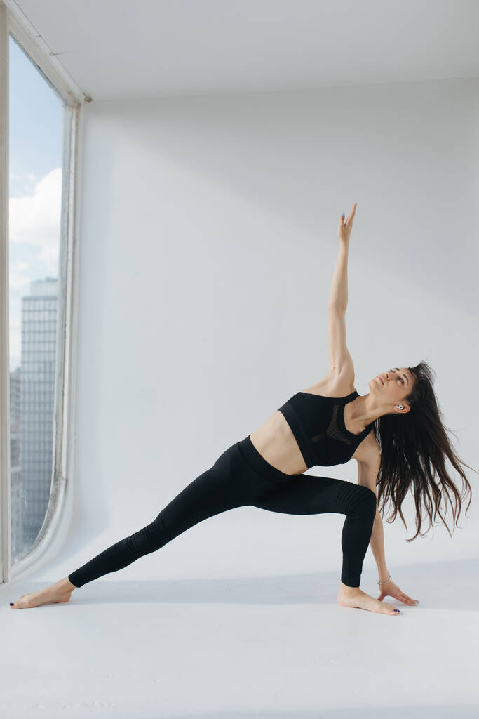 brunette armenian woman practicing runners twist pose on white floor at home - Photo, Image
