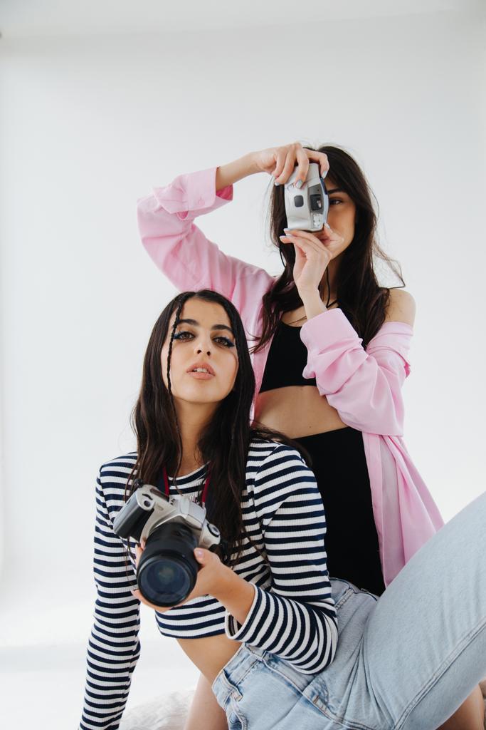 junge und stilvolle armenische Frauen mit Digitalkameras auf weißem Hintergrund - Foto, Bild